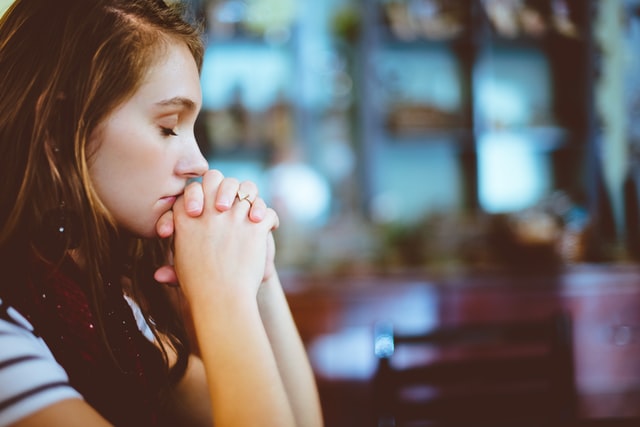 woman with folded hands and closed eyes praying, meditating or reflecting to stop anxious or worried thoughts. therapy for anxiety can help you in Tigard, OR. Discover hope with online therapy in Oregon