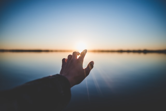hand reaching out toward sunrise against water for discover hope in therapy in Tigard, OR. You can get help for anxiety, depression, couples, trauma, pregnancy, postpartum and more with online therapy in Oregon