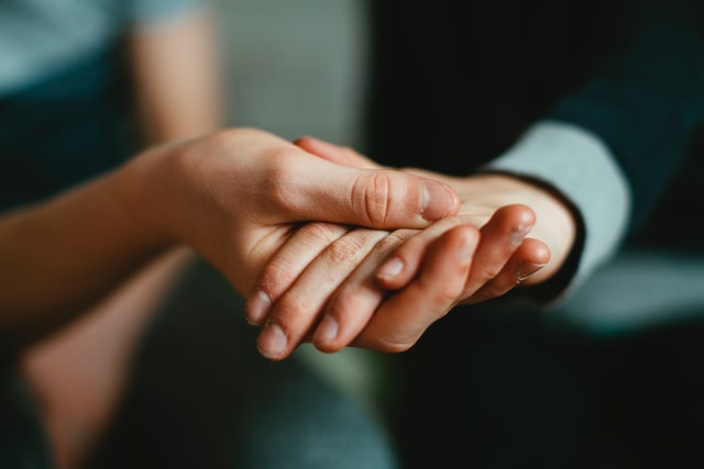 A close up of a couple holding hands. This could symbolize the stronger bonds cultivated by working with a therapist for life transitions in Tigard, OR. Learn more about life transitions counseling and other services available. 