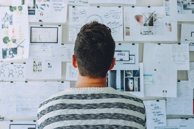 Man looking at a wall with a lot of pictures and to-do items feeling overwhelmed and worried. Learn more about anxiety counseling in Tigard, OR, and overcoming social anxiety in Oregon today. Online therapy in Oregon can help you heal.