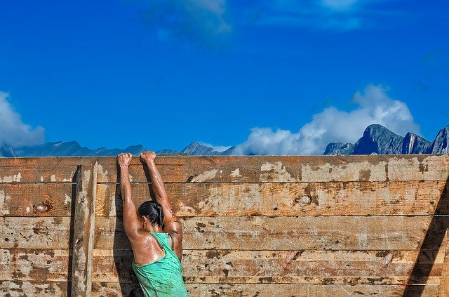 Woman hanging on to a wooden wall, climbing high to overcome her anxiety, depression, trauma and issues with boundaries in Tigard, OR. Online counseling in Oregon with Tigard therapists.