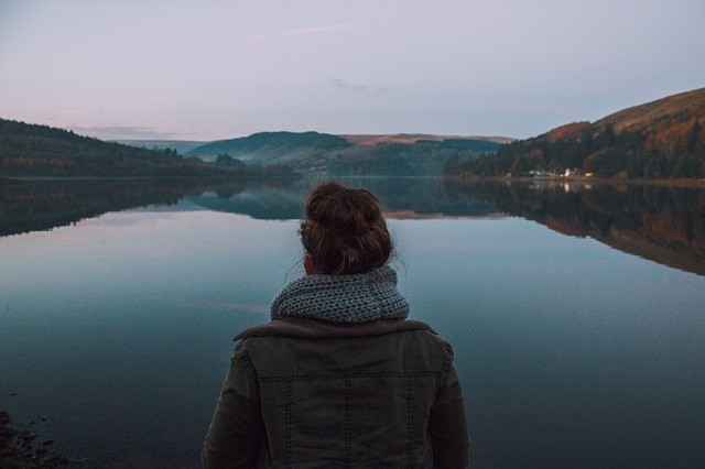 Woman looking over the lake between the mountains. You can get help with anxiety treatment and depression therapy in Tigard, OR with online therapy in Oregon with a caring therapist to discover joy.