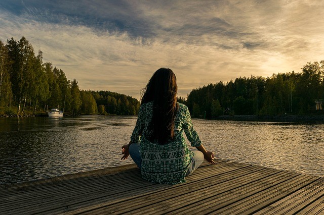 Woman sitting, doing a yoga practice on a dock overlooking the lake in Tigard, OR after therapy. Anxiety counseling in Tigard, OR, and therapy for social anxiety in Oregon can offer coping techniques for managing anxiety.