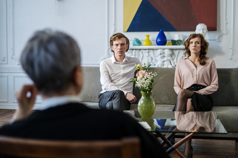Man and woman sitting apart on a couch across from a therapist with vases for decor. Couples therapy in tigard, or can help you heal and reconnect. You can get discernment counseling or couples counseling at Discover Counseling in Tigard, OR.