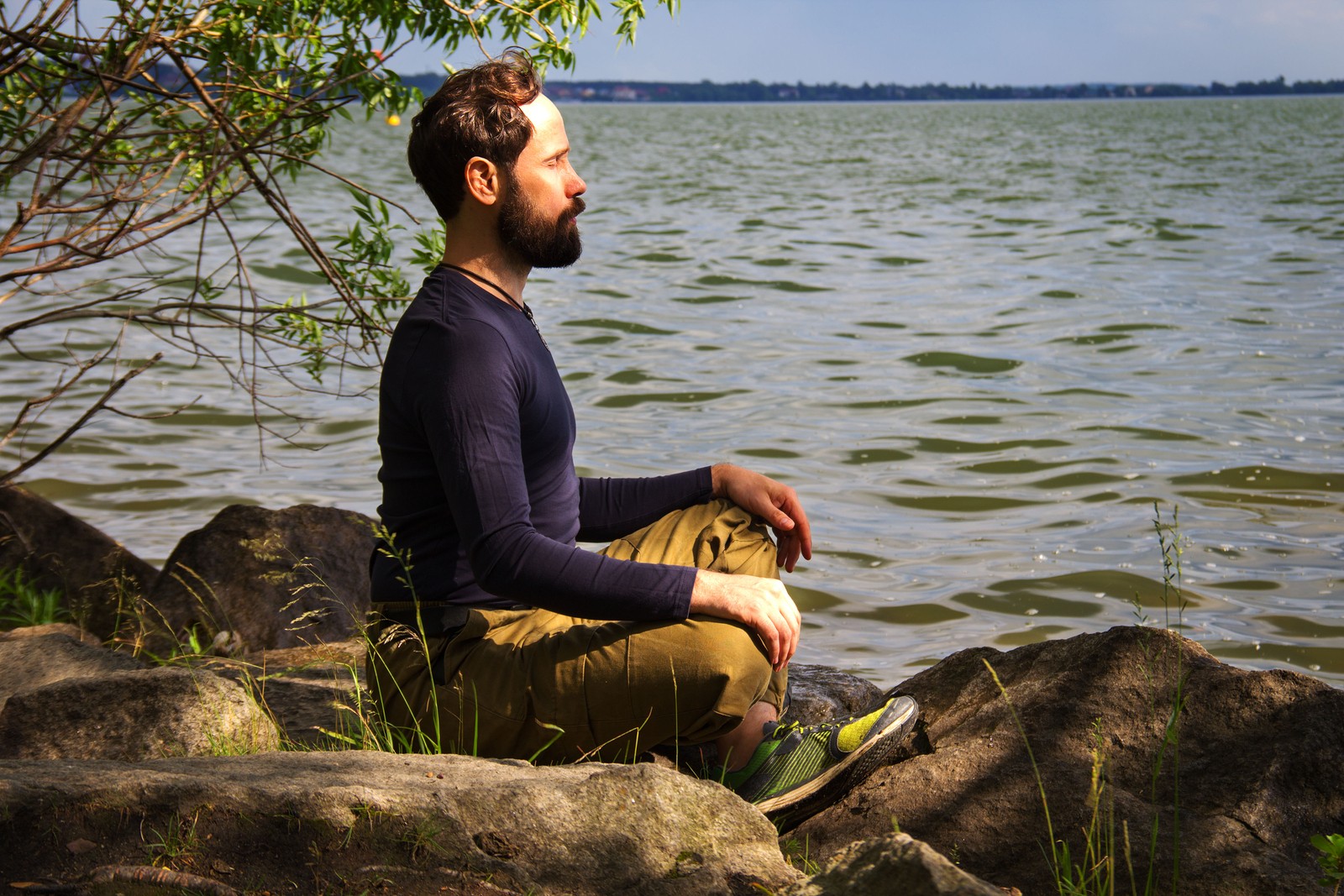 man sits by body of water meditating and thinking about maintaining healthy boundaries. He got online therapy in Oregon with an online therapist from Discover Counseling in Tigard, OR 