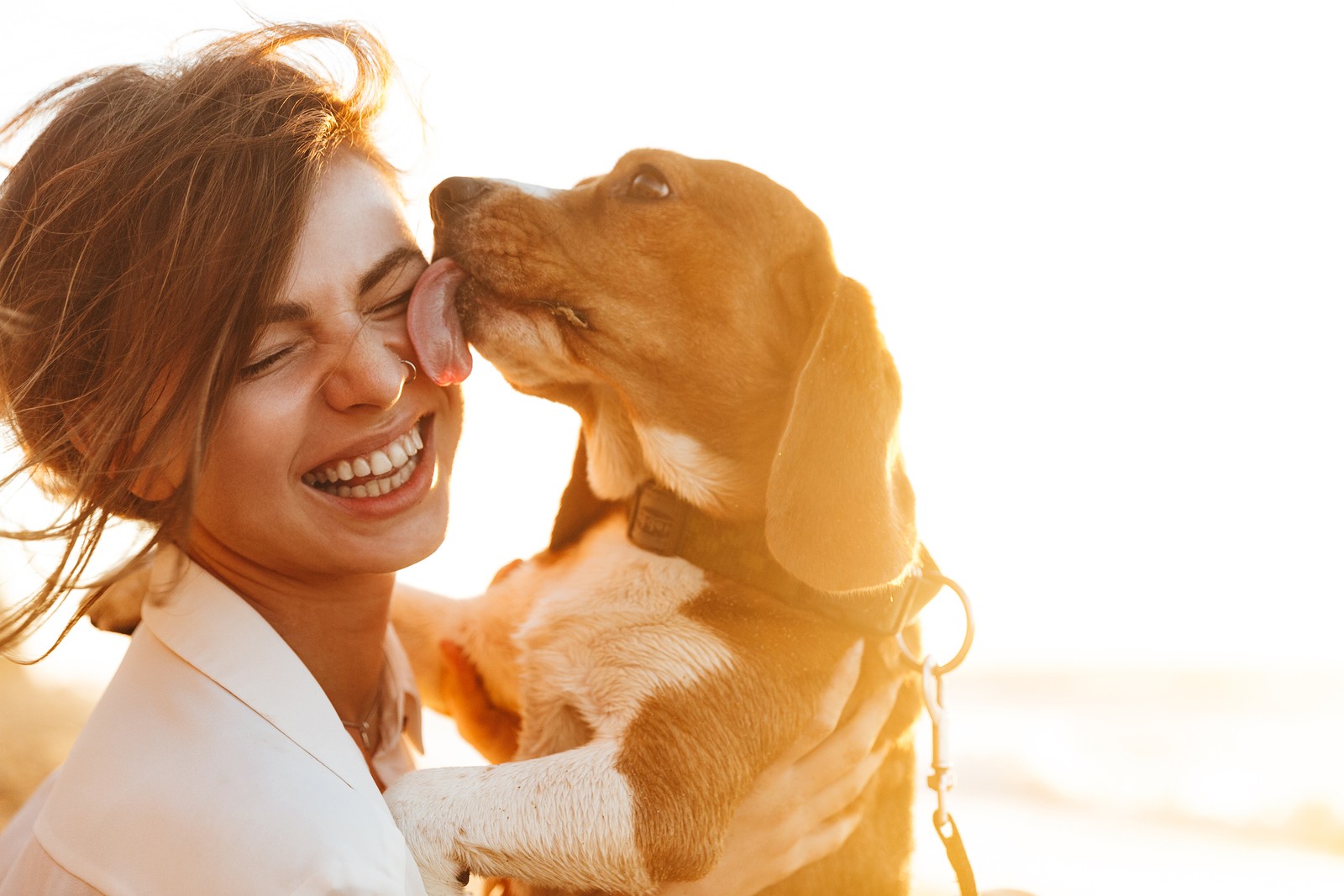 Woman holds a dog that's licking her face. she thinks about what she enjoys and what makes her happy. She also gets online therapy in Oregon with an online therapist at Discover Counseling in Tigard, OR