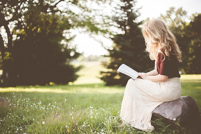 Woman sits on a rock outside reading a book. She has gotten help for anxiety, depression and coping with life transitions in Tigard, OR with an online therapist in Oregon at Discover Counseling.