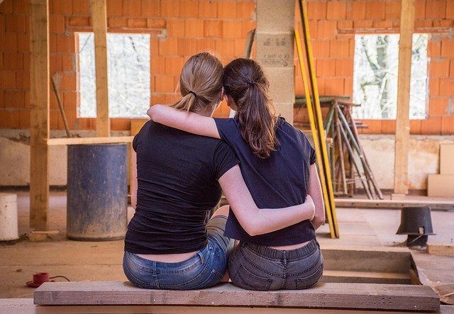 Two women embrace each other in an open room, with building materials all around. Anxiety therapy in Tigard, OR with a skilled counselor can help you feel better. Start online therapy in Oregon today.