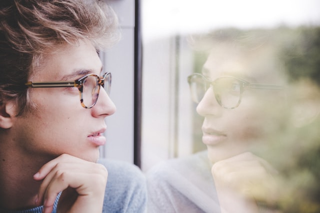 photo of a gender neutral individual looking out a window. This represents determining what you body is trying to tell you about your emotions and anxiety. To learn more get anxiety counseling in Tigard, OR with a therapist at Discover Counseling