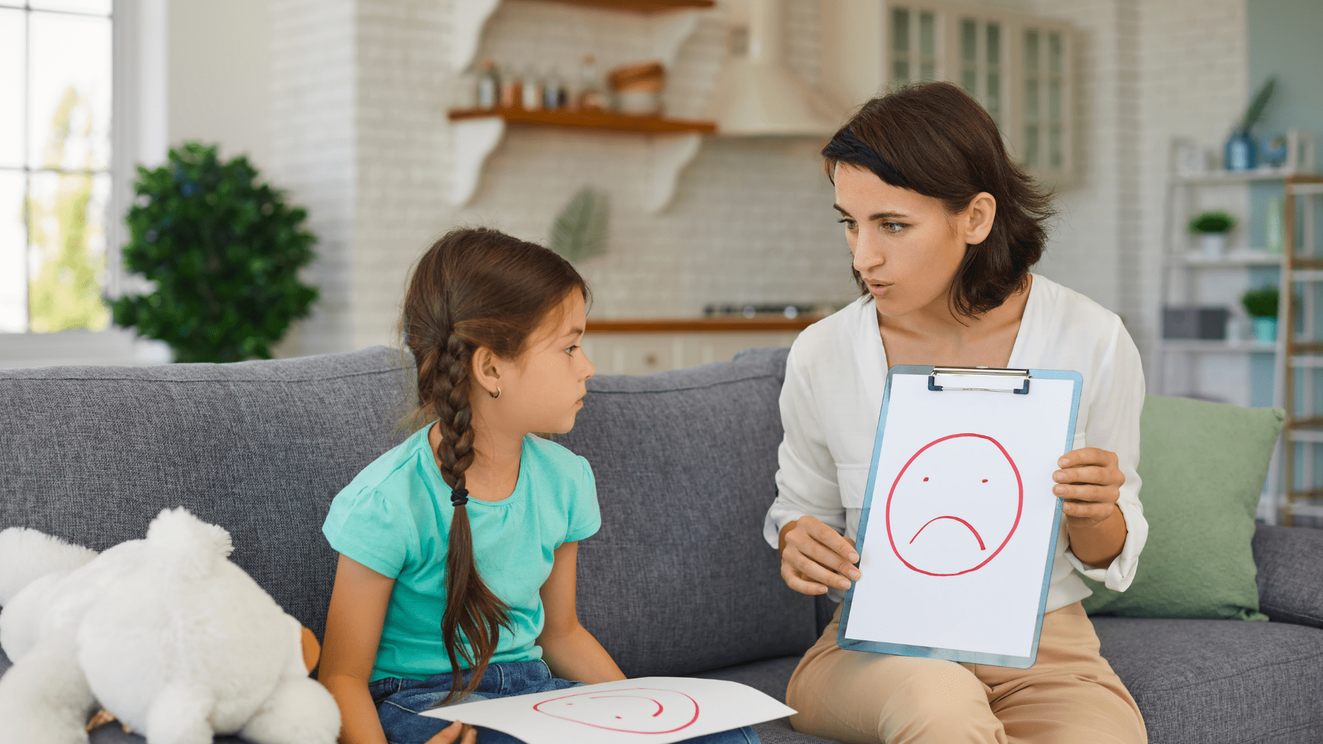Child therapist holding up a feelings image of a frowning face to a child. This is a skill used in child counseling in Tigard, OR or with online therapy in Oregon for children and adolescents.