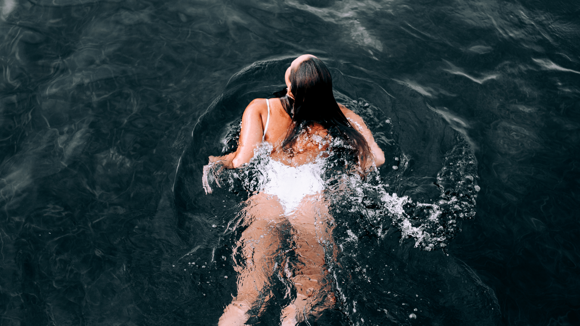 Image of a woman in a white swimsuit swimming in calm waters. Start embracing your body with the help of an anxiety counselor Tigard. Through therapy for anxiety you can start living your happiest life. Regain your joy in stress counseling in Tigard, OR.