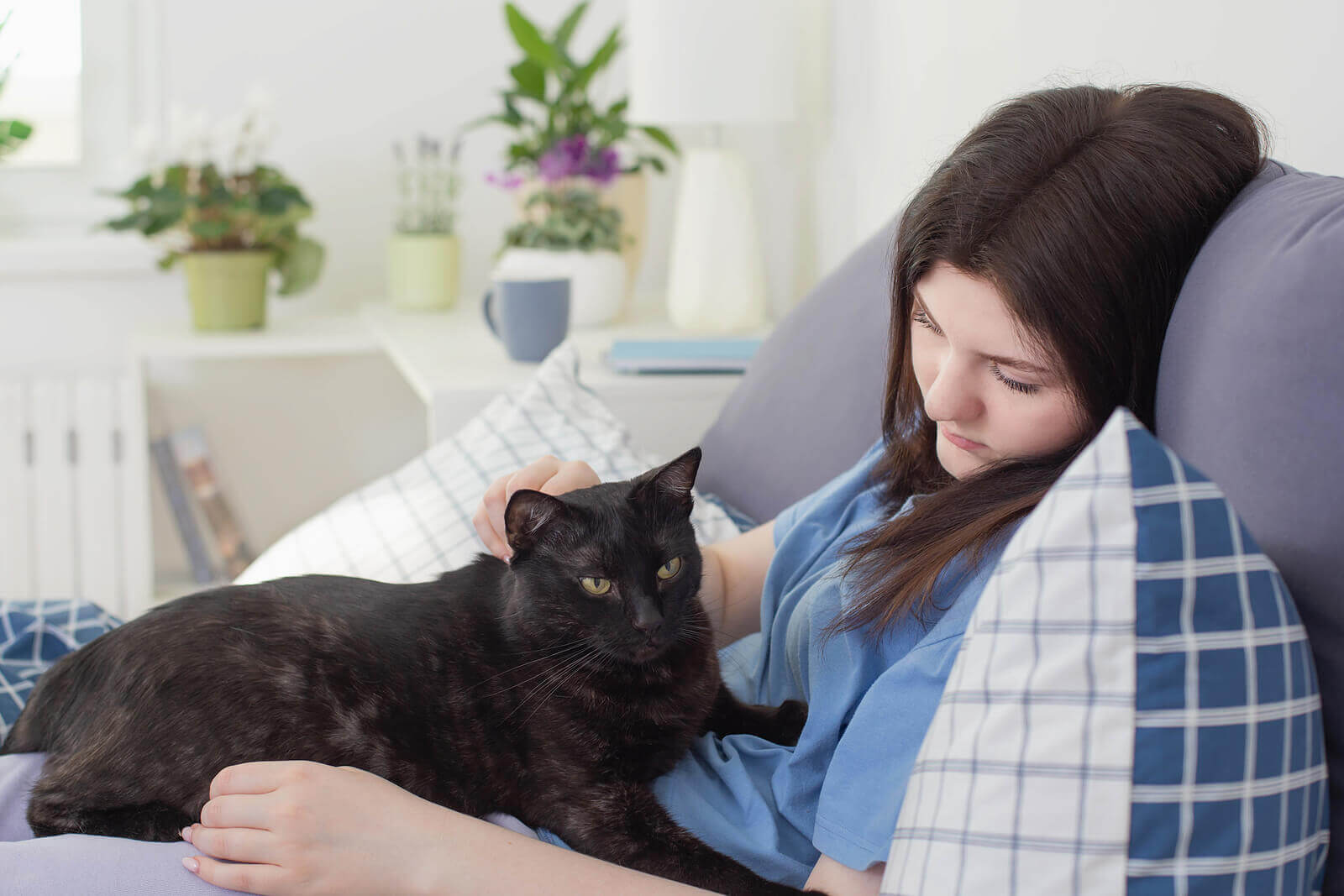 Image of a teenager looking sad petting her cat show the importance of having a support system such as pets, friends, and an online therapist to help you get over it. Life transition counseling is there to make something ending easier. Processs the emotions with therapy for life transitions.