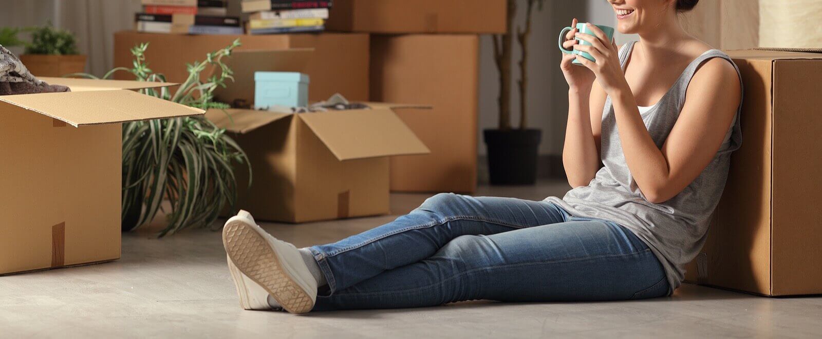 Image of a smiling woman surrounded by moving boxes showing how something coming to an end can be easier with life transition counseling in Tigard, OR. Through therapy for life transitions you can learn to get over it with the support of an online therapist in Oregon.