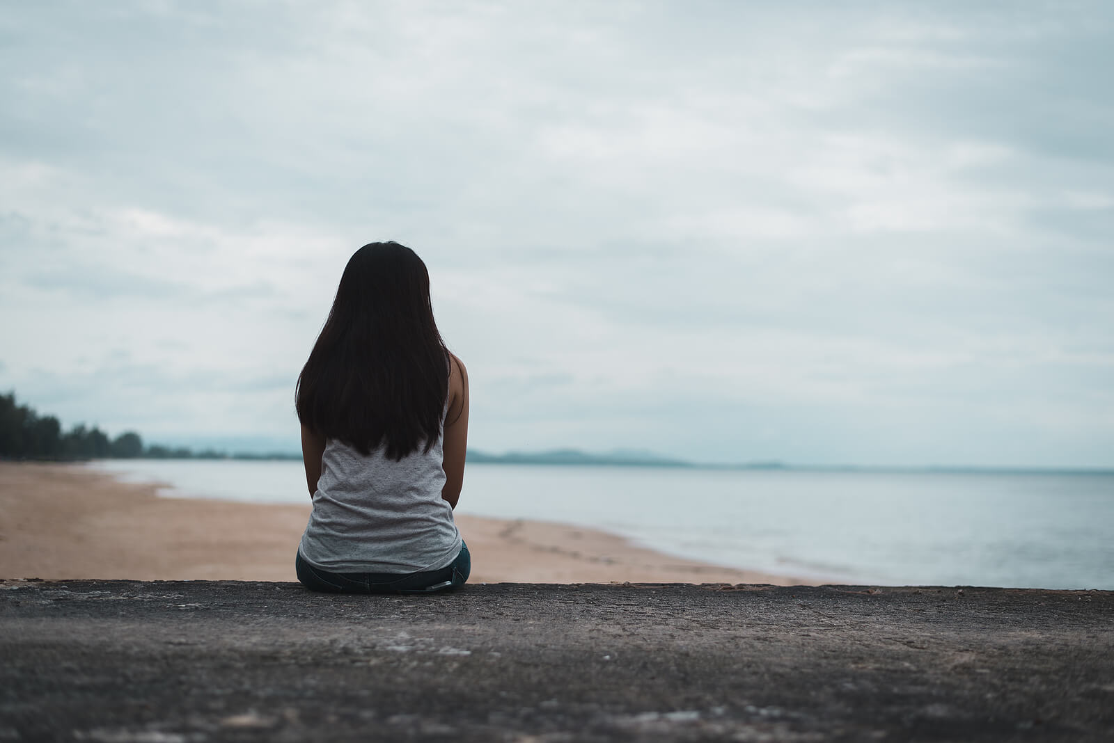 Woman sitting by the ocean contemplating life representing someone struggling with boundaries in their life. Learn to effectively set boundaries through online therapy in Oregon.