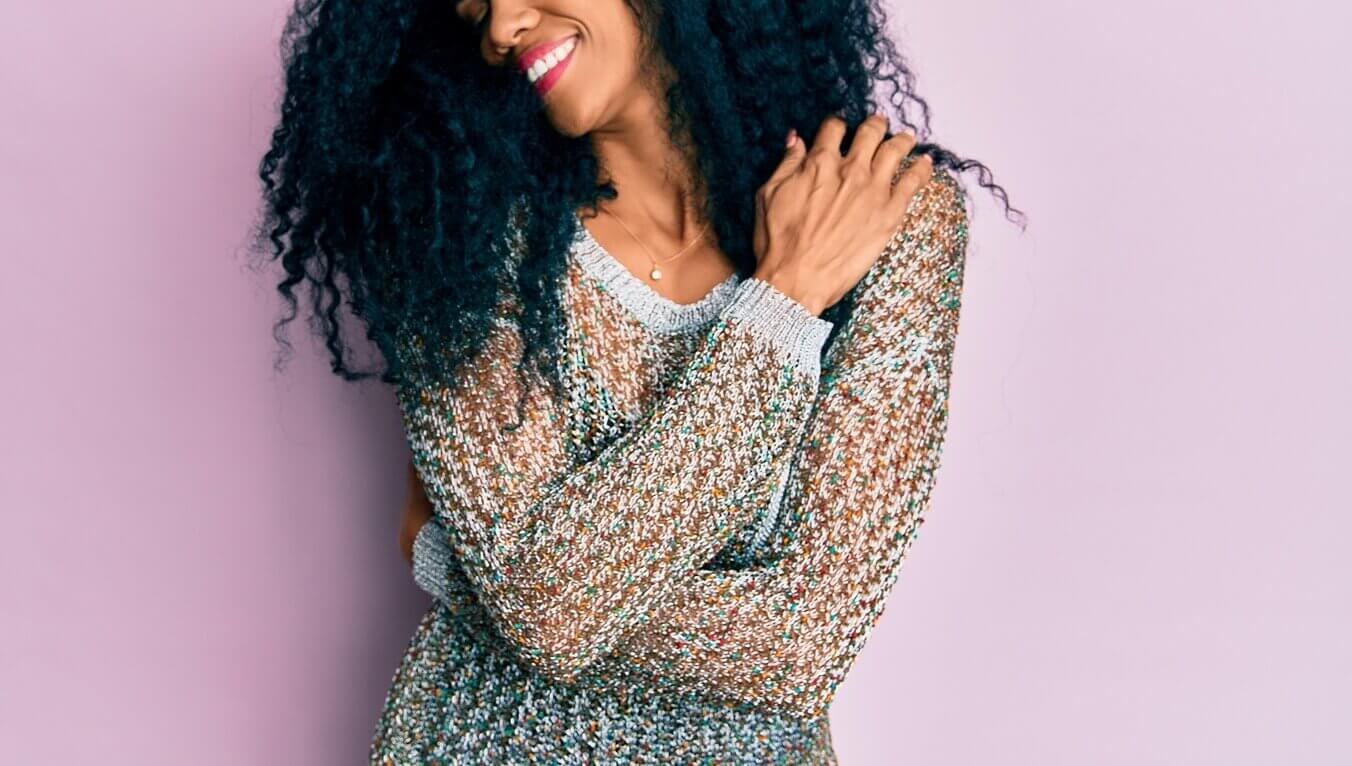 Image ofa woman hugging herself in front of a pink background showing the confidence you can gain from online therapy in Oregon. You can start loving your life and your self with stress counseling in Tigard, OR with an Oregon online therapist .