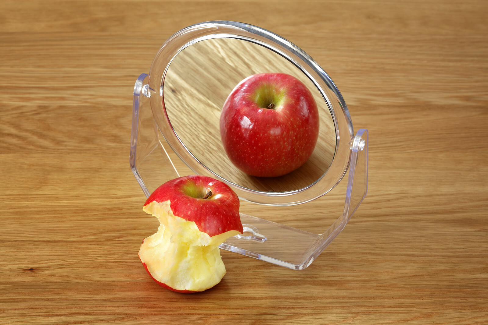 An eaten apple in the front of a mirror appears untouched in the reflection. This could represent the struggles of body image that counseling in Tigard, OR can offer support in addressing. Search for "therapist Tigard" or Oregon online therapy to learn more about the support an online therapist in Oregon can offer. 
