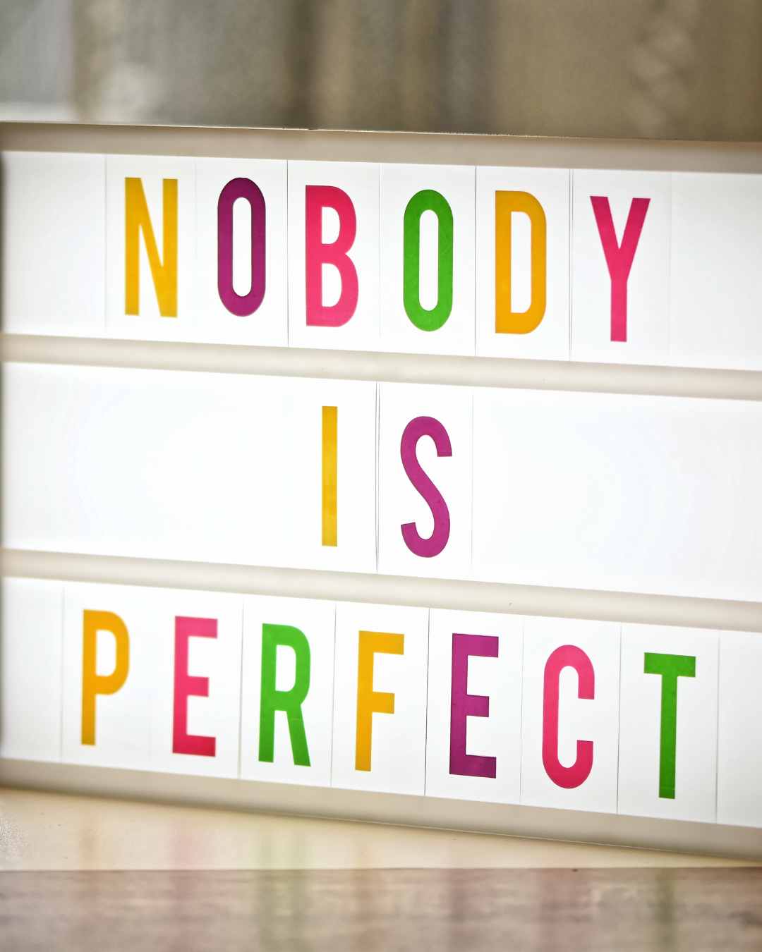 A lightbox with the words "NOBODY IS PERFECT" in colorful letters. Perfectionism in women in Tigard, OR can be helped with therapy.
