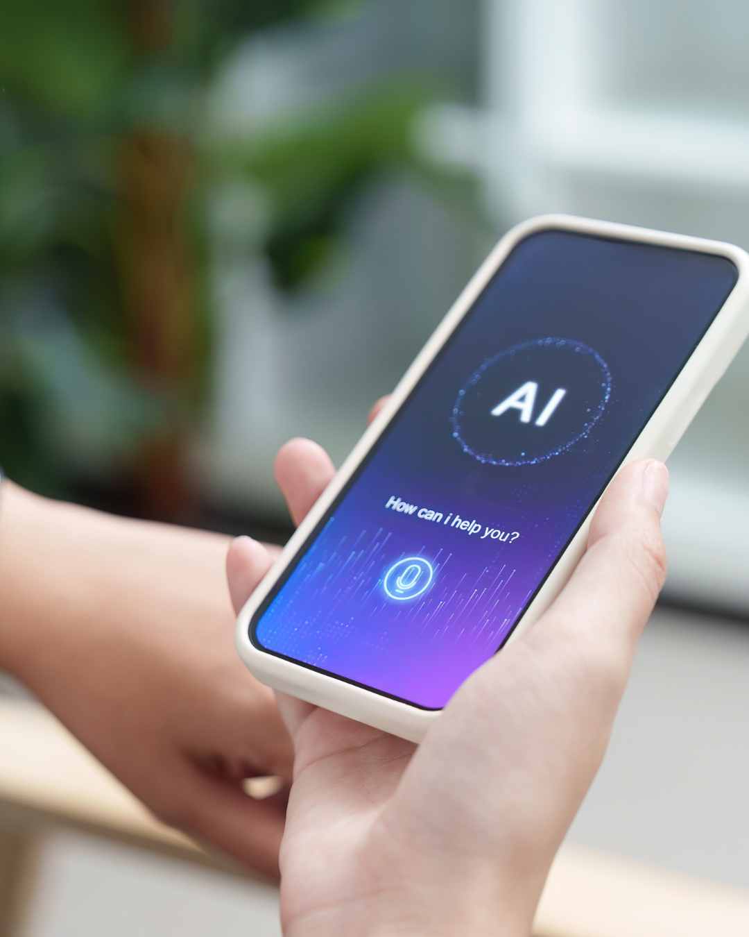 A person holds a smartphone displaying an AI virtual assistant interface with the text "How can I help you?" on the screen. Thinking about using AI for therapy? Learn why AI cannot replace real therapy and how human connection supports healing in Tigard, OR.